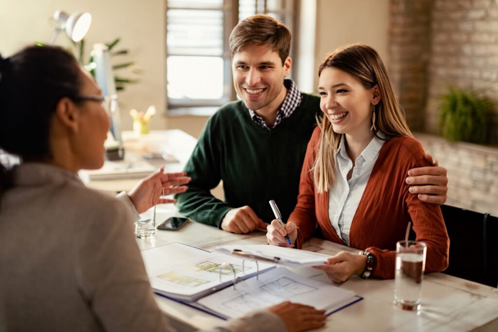 young-happy-couple-signing-contract-while-being-meeting-with-insurance-agent-office